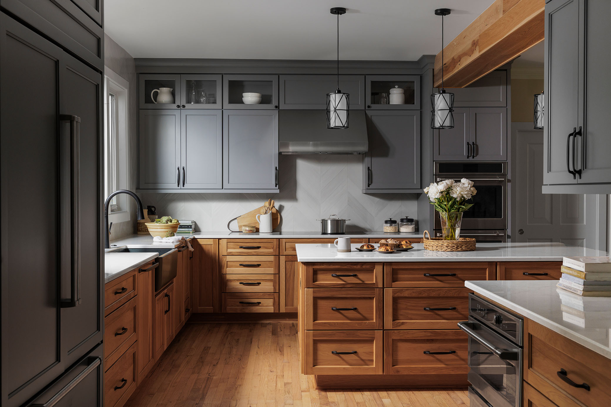 Two-tone custom kitchen in Fulton MD with slate grey upper cabinets, natural oak wood island, and herringbone backsplash captured by interior photographer
