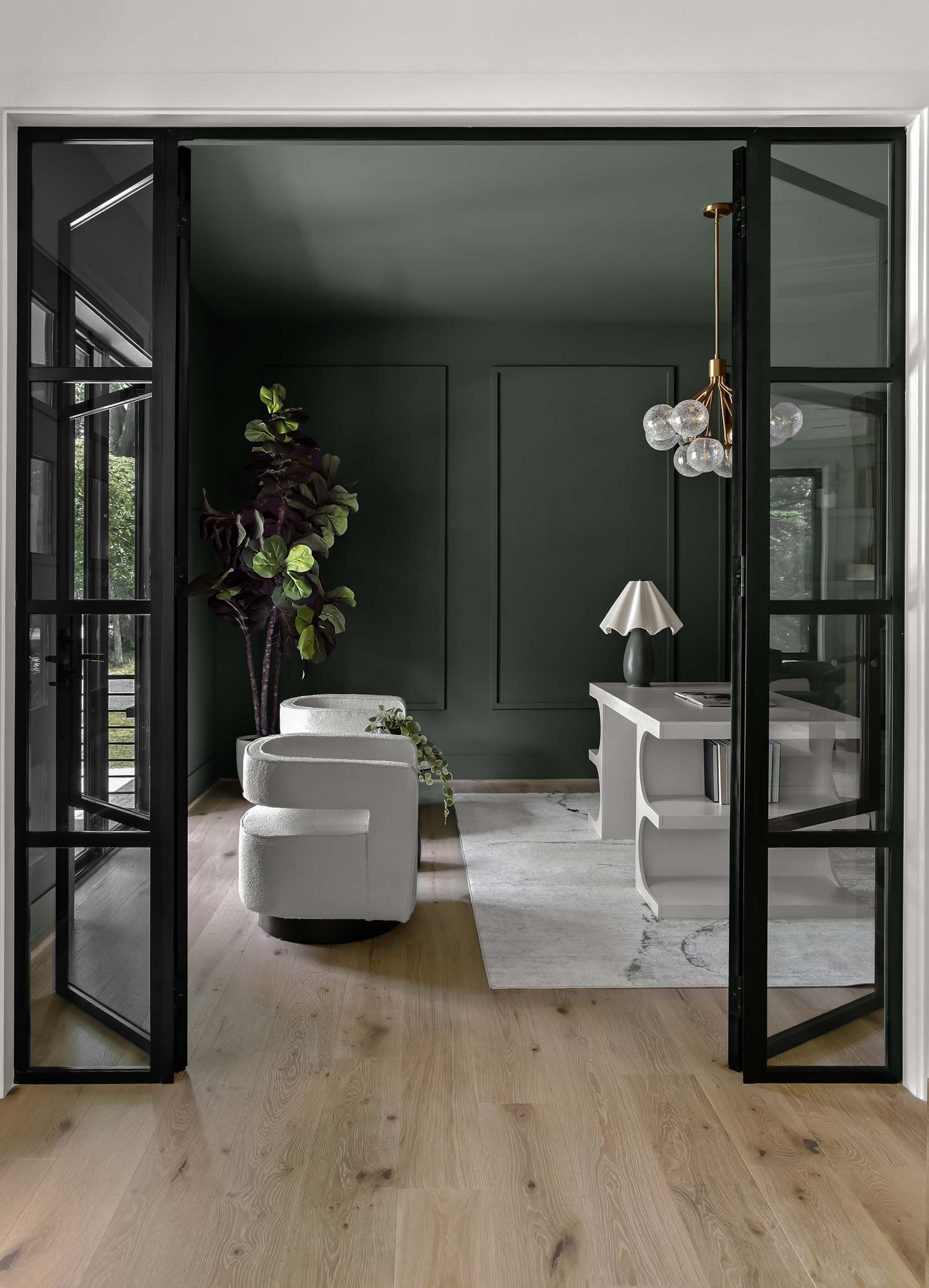 Howard County MD interior design featuring dark forest green wainscoting walls, black steel-grid doors, and modern white bouclé armchairs